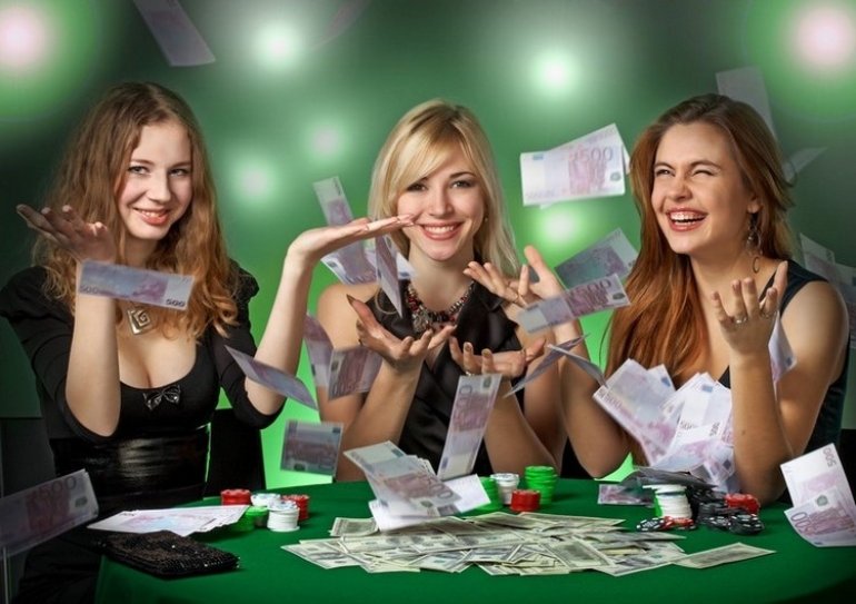 Три блондинки обыграли казино и подбрасывают вверх денежные купюры, сидя за игорным столом