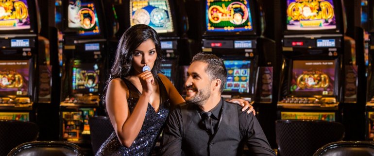 Богатый мужчина играет в казино в компании привлекательной девушки