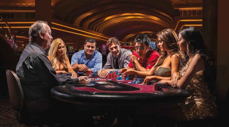 Компания молодых красиво одетых людей за игрой в покер в казино вип-уровн