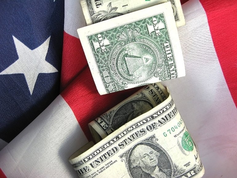 Пара долларовых купюр на флаге США
