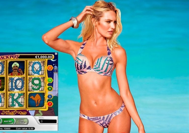 Стройная блондинка в купальнике позирует на пляже рядом с игровым автоматом