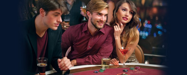 Молодые обеспеченные мужчины играют в казино, а привлекательная блондинка распивает коктейли, наблюдая за их игрой