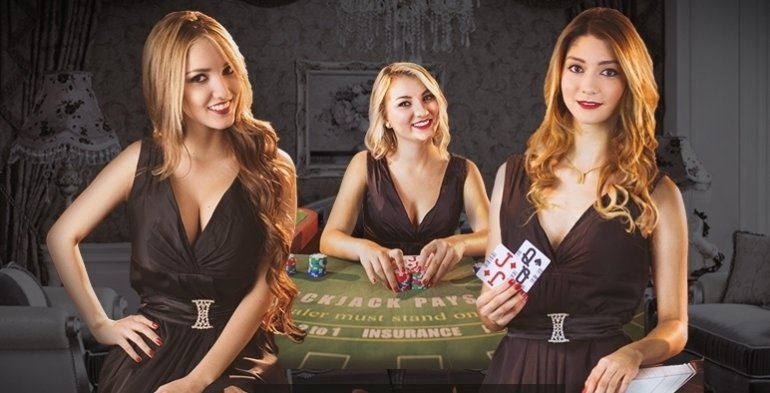 Три красотки-блондинки в сексуальных черных платьях позируют у стола для блэкджека, приветливо улыбаясь