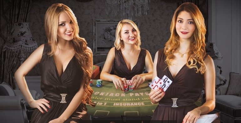 Три белокурых девушки в черных обтягивающих платьях позируют у стола для игры в блэкджек