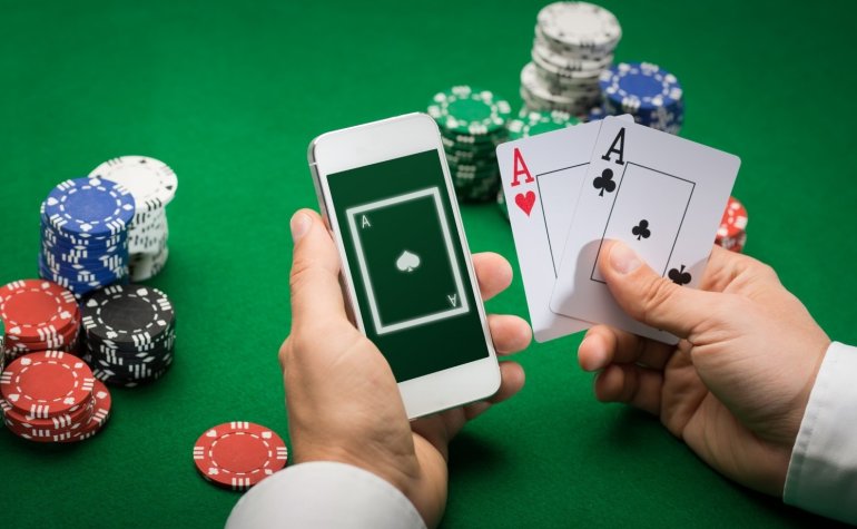Игрок в покер держит в руках смартфон и два туза