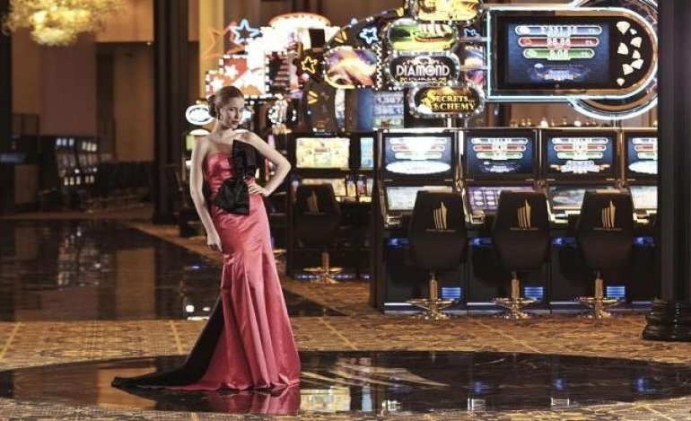 Женщина в роскошном платье стоит в зале с игровыми автоматами