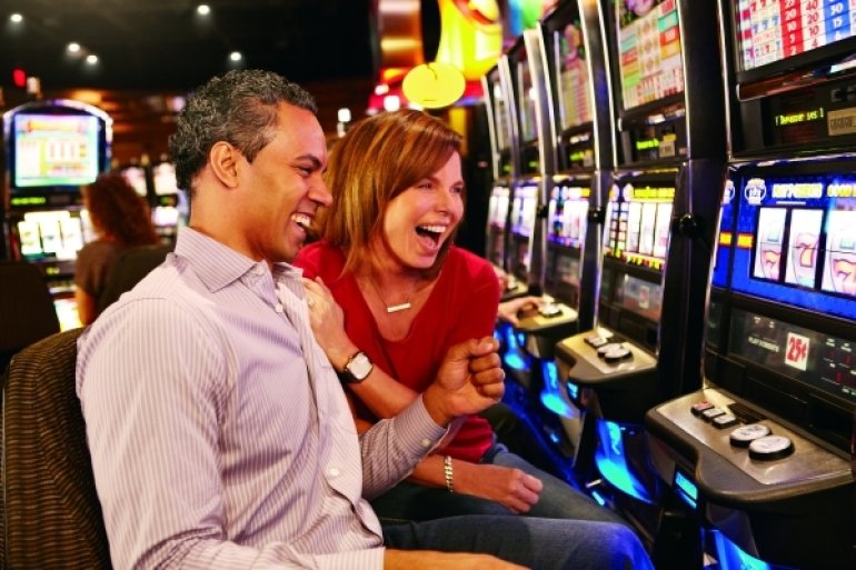 Мужчина и женщина в восторге от своего выигрыша на игровом автомате в казино