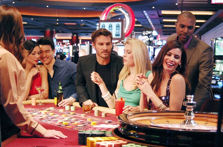 Компания молодых красивых людей играет в рулетку в дорогом казино
