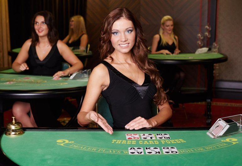 Привлекательная рыжеволосая девушка-крупье ждет игроков за столом для трехкарточного покера