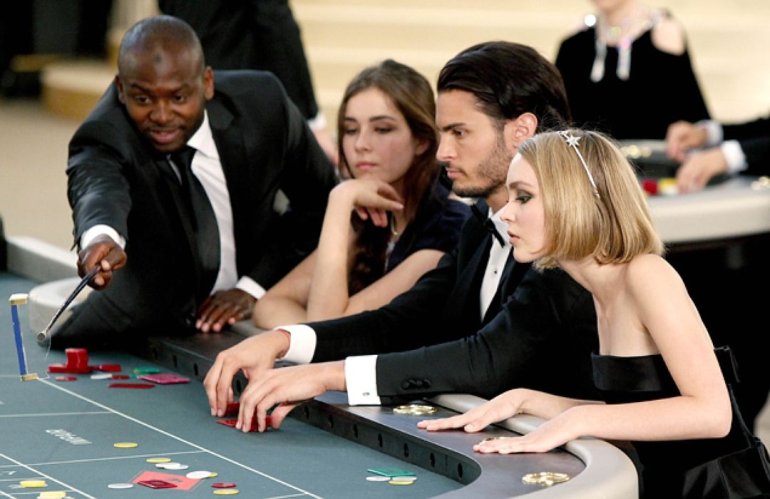 Элегантные игроки за столом для рулетки в дорогом казино