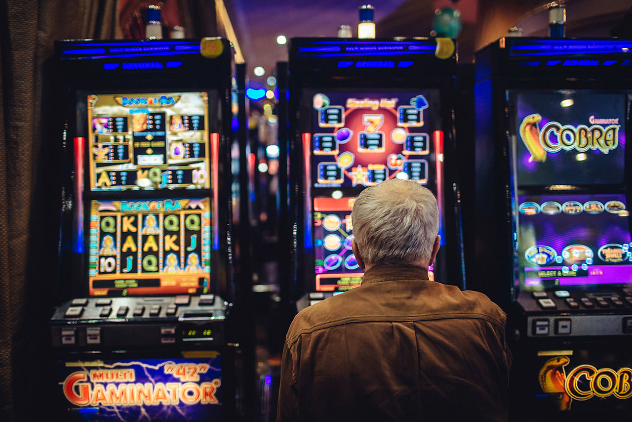 Пожилой человек за игровым автоматом
